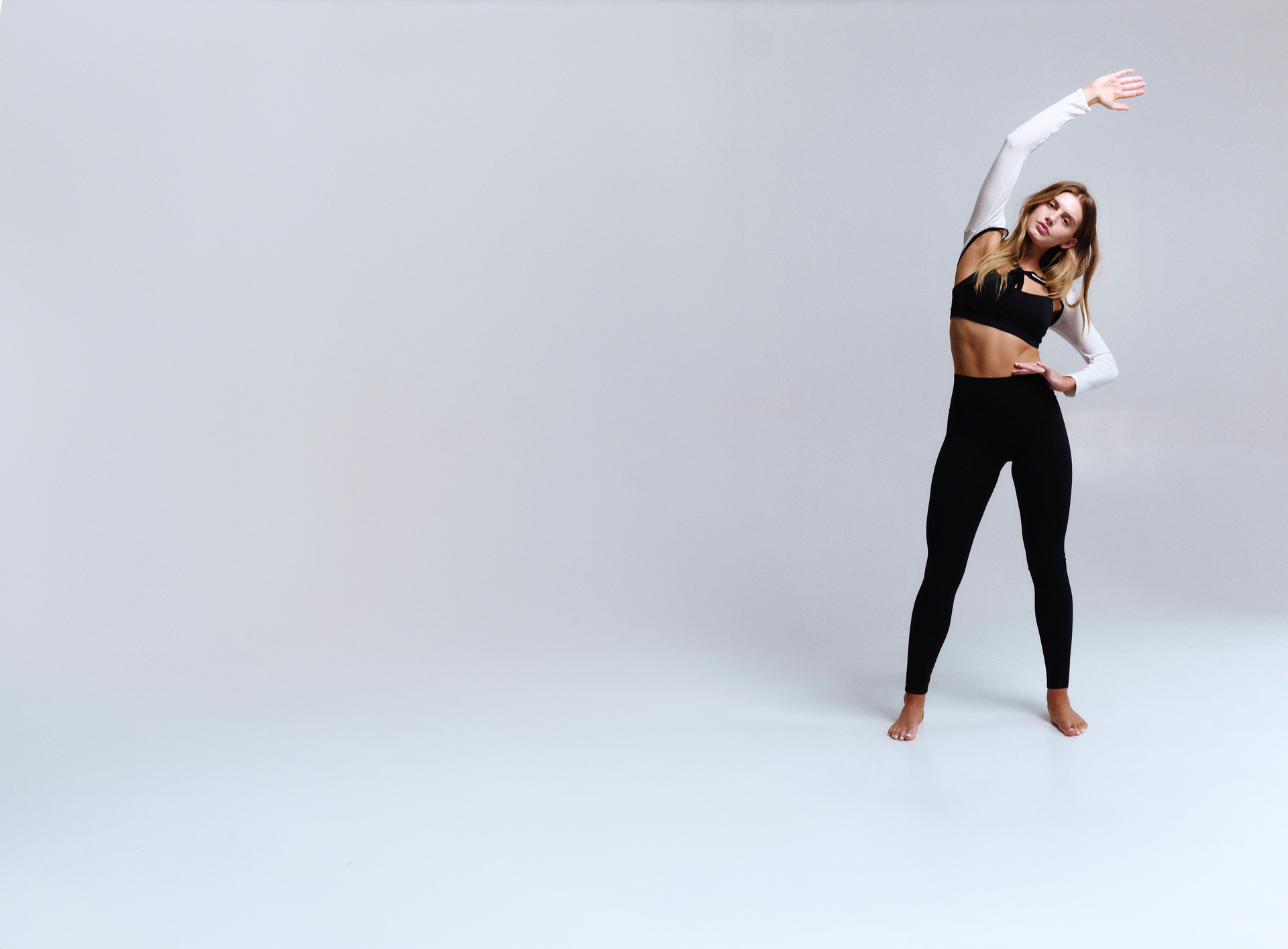 Woman in black athletic wear posing on a white background